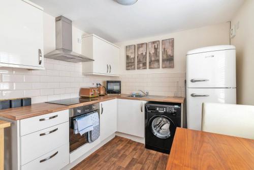 cocina con armarios blancos, lavadora y secadora en Coach House - Lovely 1 Bedroom Flat near Derby City Centre, en Derby