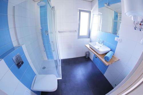 a blue and white bathroom with a sink and shower at Osada Natura in Śliwin