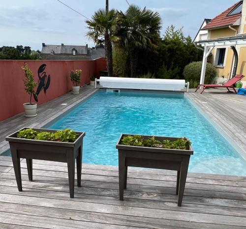 a swimming pool with two tables with plants in them at Le Clos du Lupin in Saint-Coulomb