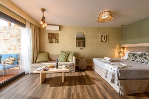 a bedroom with a bed and a couch and a table at Esperides Resort Crete, The Authentic Experience in Hersonissos