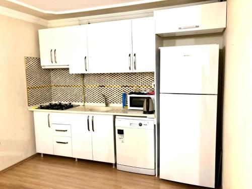 a kitchen with white cabinets and a white refrigerator at Halic apart hotel in Yalova