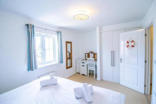 a white bedroom with a bed and a window at Beachside Cottage - Camber Sands - Close to beach in Camber