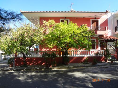 ein rotes Haus mit Bäumen davor in der Unterkunft Villa Mary Galini in Ireo