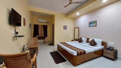 a bedroom with a bed and a desk and a television at Goroomgo Silicon Residency Puri Near Sea Beach - Parking & Lift Facilities - Best Hotel in Puri in Puri