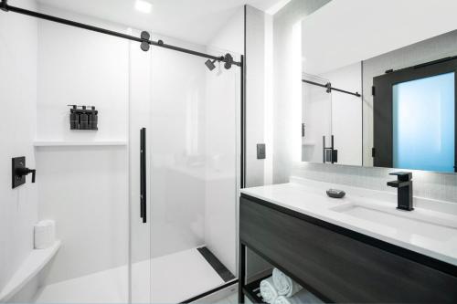 La salle de bains blanche est pourvue d'un lavabo et d'une douche. dans l'établissement The Artisan at Tuscan Village, Salem, a Tribute Portfolio Hotel, à Salem