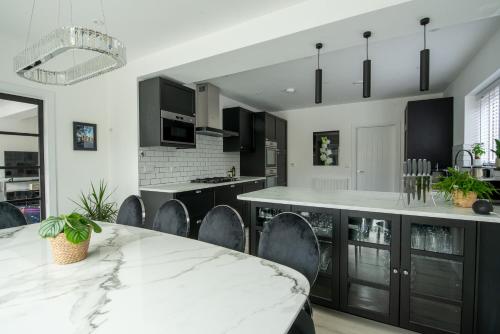 uma cozinha com armários pretos e uma mesa e cadeiras em mármore em Maycliffe em Shanklin