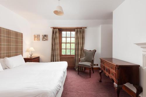 a bedroom with a bed and a desk and a chair at Tulloch Castle Hotel ‘A Bespoke Hotel’ in Dingwall