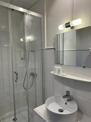 a bathroom with a shower and a sink and a mirror at Hôtel Du Centre Annemasse in Annemasse