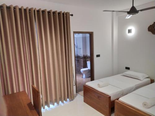 a bedroom with two beds and a window with curtains at Kandy Lotus Chalet in Kandy
