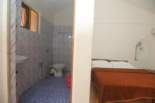 a bedroom with a bed and a bathroom with a toilet at Pritams Cottages Guest House in Palolem