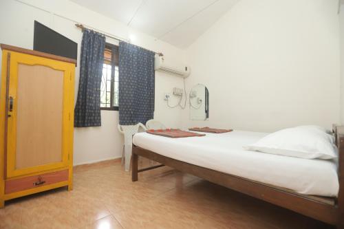 a small bedroom with a bed and a window at Pritams Cottages Guest House in Palolem