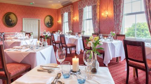 a dining room with white tables and chairs and windows at Wentworth Hotel in Aldeburgh