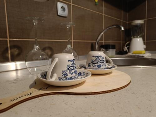 three cups and saucers on a cutting board on a kitchen counter at Apartman U2 in Veliko Gradište