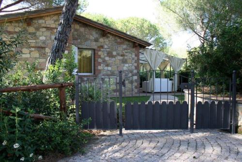 a stone house with a black fence and a yard at Villaggio I Sorbizzi in Marina di Bibbona