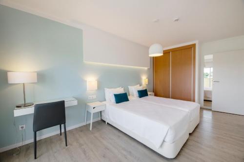 1 dormitorio con 1 cama blanca grande y escritorio en AlvorMar Apartamentos Turisticos, en Alvor