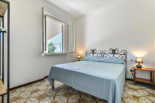 Schlafzimmer mit einem Bett mit blauer Bettdecke und einem Fenster in der Unterkunft Casa Camilla in Procchio
