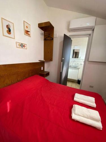 a bedroom with a red bed with two towels on it at Depto. excelente ubicación in Villa Marini