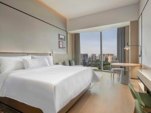 a hotel room with a white bed and a large window at Element Guangzhou Baiyun in Guangzhou