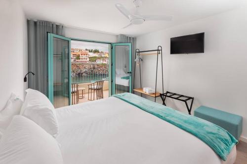 1 dormitorio con cama blanca y balcón en Villa Belafonte en Câmara de Lobos