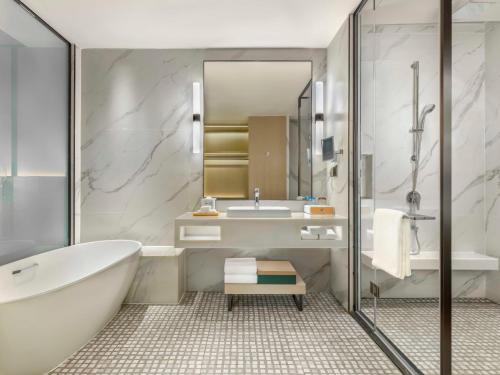 een badkamer met een bad, een wastafel en een spiegel bij Element Guangzhou Baiyun in Guangzhou