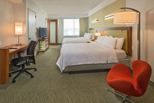 SpringHill Suites by Marriott New York LaGuardia Airport في كوينز: غرفة فندقية بسريرين ومكتب وكرسي