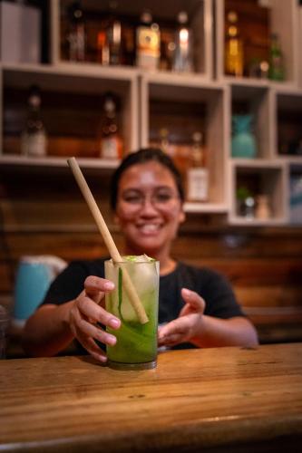 a woman sitting at a table with a green drink at My Green Hostel in San Vicente