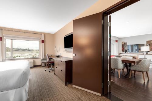 a hotel room with a bed and a desk and a kitchen at Four Points by Sheraton Kelowna Airport in Kelowna
