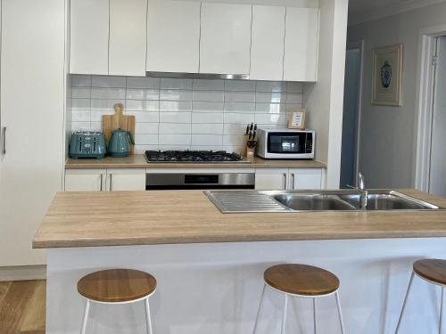 una cucina con lavandino e bancone con sgabelli di Motion Place - Mt Duneed - Geelong, Surf Coast & Great Ocean Road a Mount Duneed