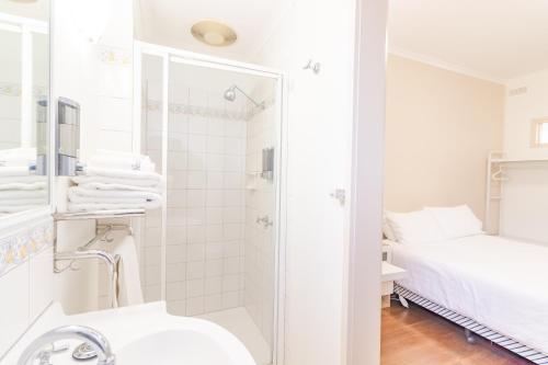 a white bathroom with a shower and a bed at Warburton Lodge in Warburton