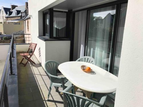 une table blanche et des chaises sur un balcon dans l'établissement Grand duplex familial au cœur de Perros-Guirec, à Perros-Guirec