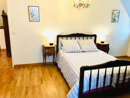 - une chambre avec un lit, 2 tables de chevet et un lustre dans l'établissement Grand duplex familial au cœur de Perros-Guirec, à Perros-Guirec