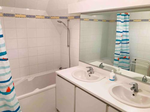 une salle de bain avec deux lavabos, un miroir et une baignoire dans l'établissement Grand duplex familial au cœur de Perros-Guirec, à Perros-Guirec