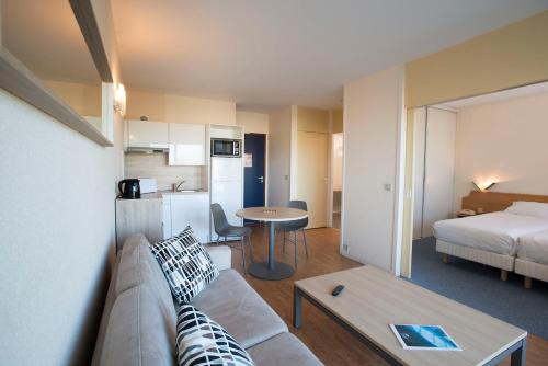 une chambre d'hôtel avec un canapé et un lit dans l'établissement Residence Les Chenes, à Saint-Paul-lès-Dax