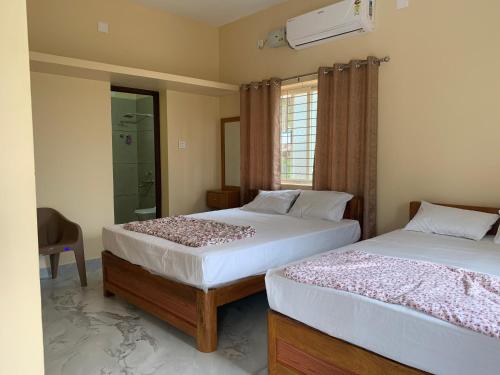 a bedroom with two beds and a glass shower at Panchavati Homestay in Malpe