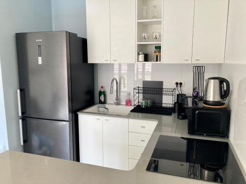 a kitchen with white cabinets and a stainless steel refrigerator at Lovely New Private Duplex in Prime City Center location in Jerusalem
