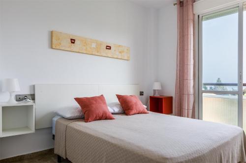 Un dormitorio con una cama con almohadas rojas y una ventana en A&N Torreon del Carmen, en Algarrobo Costa