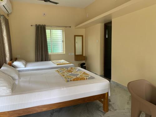 two beds in a room with a window at Panchavati Homestay in Malpe
