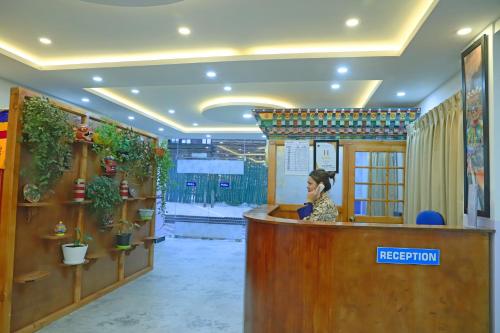 a woman sitting at a reception desk in a room at The BD Hotel in Thimphu