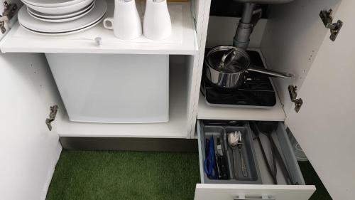 - une cuisine avec une armoire blanche avec des assiettes et des ustensiles dans l'établissement Small and Cozy Rooms - G10, à Valence
