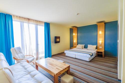 a hotel room with a bed and a couch and a table at Mirage Hotel in Nesebar