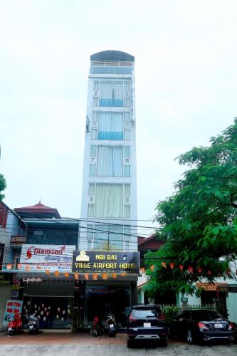 a tall building with cars parked in front of it at Noi Bai Ville Airport Hotel in Hanoi