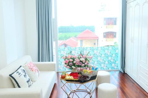 sala de estar con sofá blanco y mesa con flores en Noi Bai Ville Airport Hotel, en Hanói