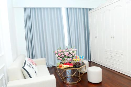 a living room with a white couch and a table with flowers at Noi Bai Ville Airport Hotel in Hanoi
