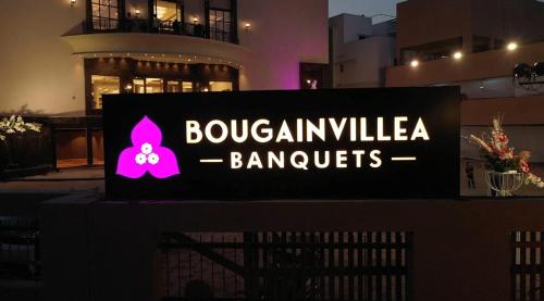 una señal para un edificio con un edificio en el fondo en Bougainvillea Banquets and Convention Centre, en Nagpur
