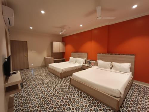 Habitación de hotel con 2 camas y TV de pantalla plana. en Bougainvillea Banquets and Convention Centre, en Nagpur