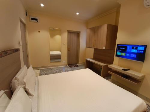 um quarto de hotel com uma cama e uma televisão de ecrã plano em Bougainvillea Banquets and Convention Centre em Nagpur