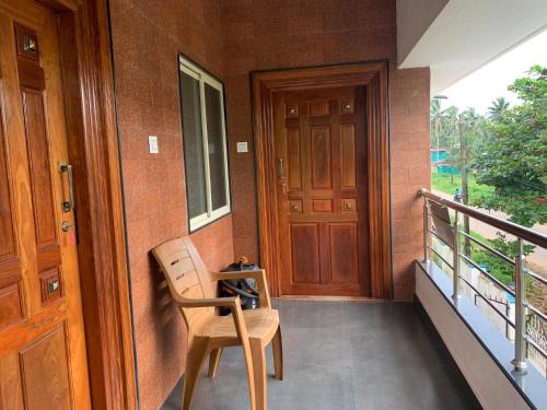 a porch with a wooden door and a wooden chair at Panchavati Homestay in Malpe