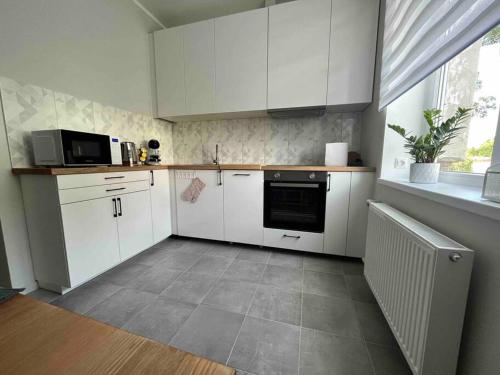 a small kitchen with white cabinets and a window at Apartment Jõesuu in Narva