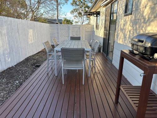 una terraza de madera con mesa, sillas y parrilla en Gullivers Guest House, en East Maitland