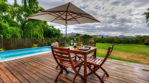 a wooden deck with a table and an umbrella at Little Oak Cottage in Greyton